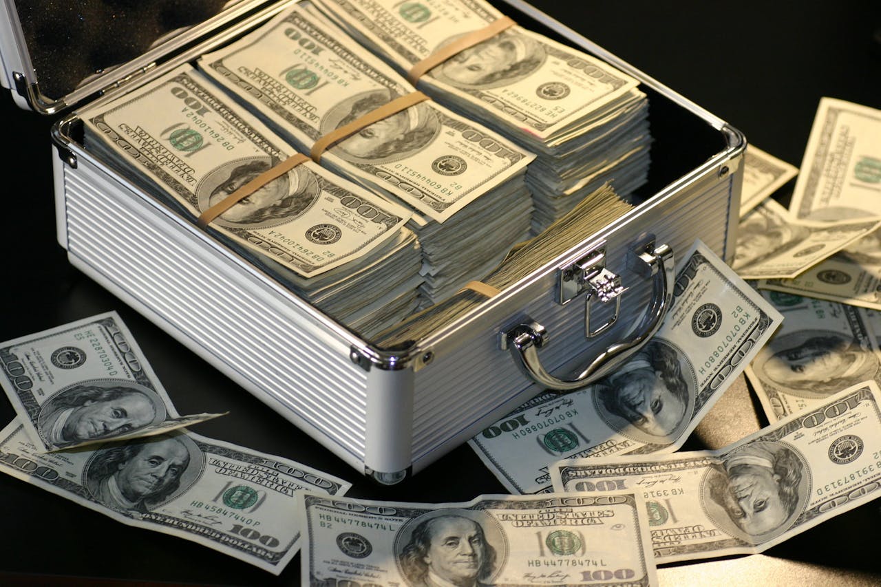 ours-journey A metallic briefcase full of US dollar bills, symbolizing wealth and investment.