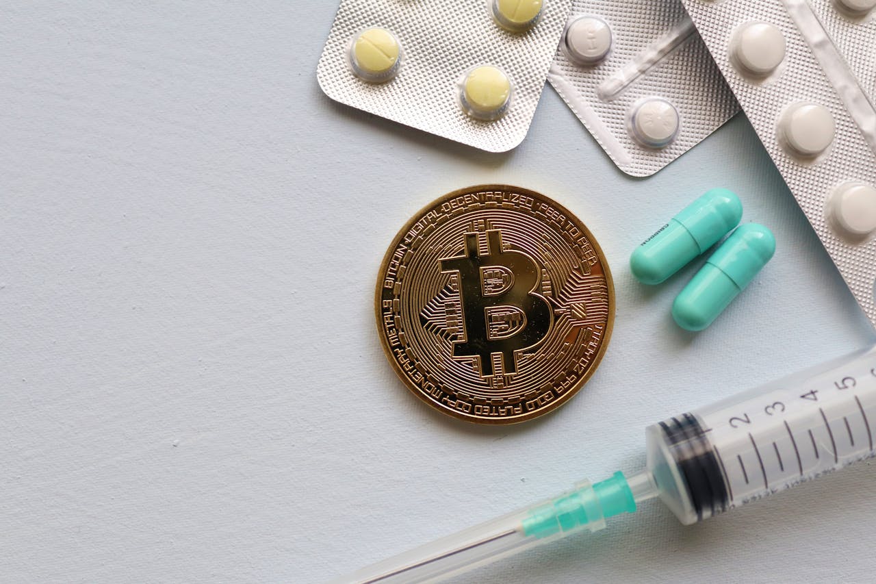 our-experience Image of a Bitcoin coin surrounded by pills and a syringe, symbolizing healthcare and finance.